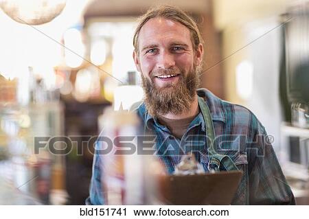 Stock Image - Caucasian server holding clipboard in cafe. Fotosearch