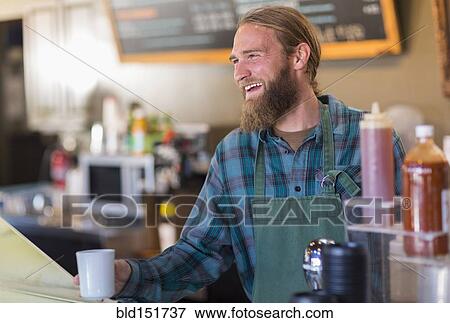 Stock Photo - Caucasian server holding cup of coffee in cafe. Fotosearch