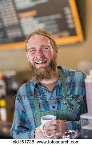 Stock Photo - Caucasian server holding cup of coffee in cafe. Fotosearch