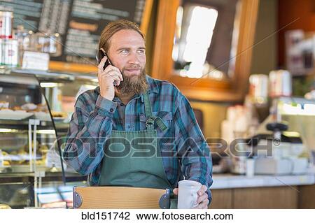Stock Image - Caucasian server talking on telephone in cafe. Fotosearch