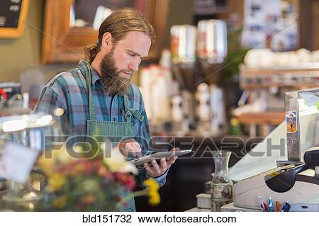 Stock Image - Caucasian server using digital tablet in cafe. Fotosearch