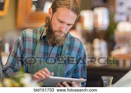 Stock Image - Caucasian server using digital tablet in cafe. Fotosearch