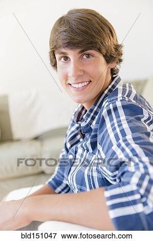 Stock Photo - Caucasian teenage boy smiling in living room. Fotosearch