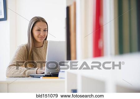 Stock Photo - Caucasian teenage girl using laptop at desk. Fotosearch