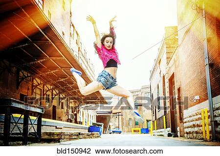 Stock Image - Caucasian woman dancing in street. Fotosearch