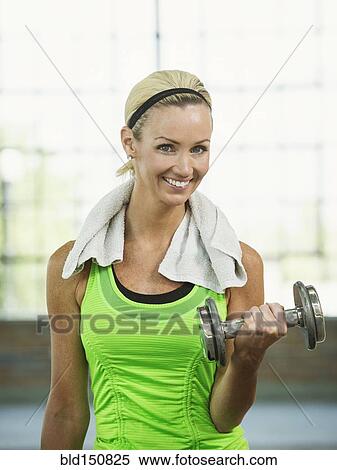 Stock Photography - Caucasian woman lifting weights in gym. Fotosearch