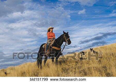 Stock Photo - Caucasian woman on horseback on grassy hill. Fotosearch