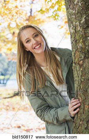 Caucasian woman peeking from behind tree View Large Photo Image Stock Photo - Caucasian woman peeking from behind tree. Fotosearch