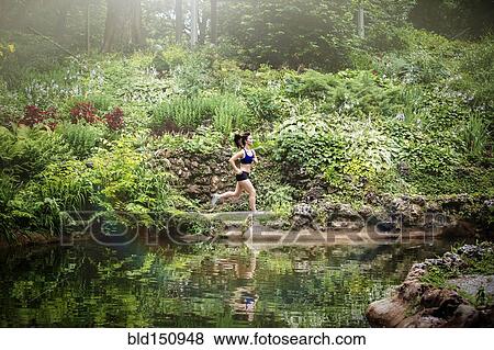 Caucasian woman running near lake in park View Large Photo Image Stock Photo - Caucasian woman running near lake in park. Fotosearch