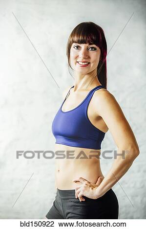 Stock Image - Caucasian woman smiling in sports bra. Fotosearch
