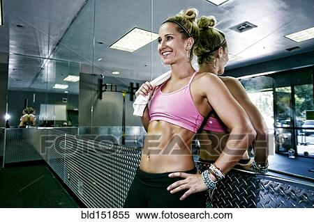 Stock Photography - Caucasian woman standing at mirror in gym. Fotosearch