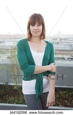 Stock Photograph - Caucasian woman standing on urban rooftop. Fotosearch