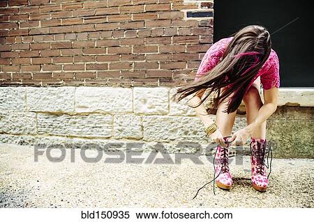 Caucasian woman tying boots on sidewalk View Large Photo Image Stock Photography - Caucasian woman tying boots on sidewalk. Fotosearch