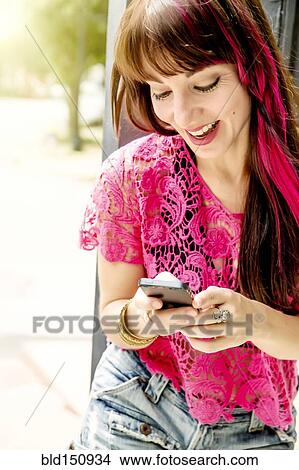 Picture - Caucasian woman using cell phone on sidewalk. Fotosearch