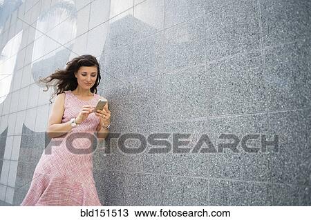 Stock Image - Caucasian woman using cell phone outdoors. Fotosearch