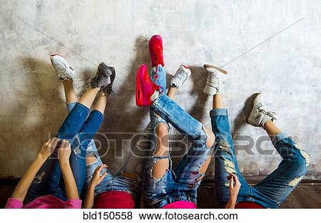 Stock Photo - Caucasian women admiring their sneakers against wall. Fotosearch