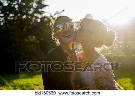 Stock Image - Caucasian women kissing in backyard. Fotosearch