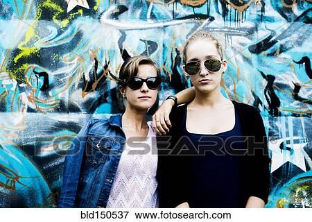 Caucasian women posing near graffiti wall View Large Photo Image Stock Photo - Caucasian women posing near graffiti wall. Fotosearch