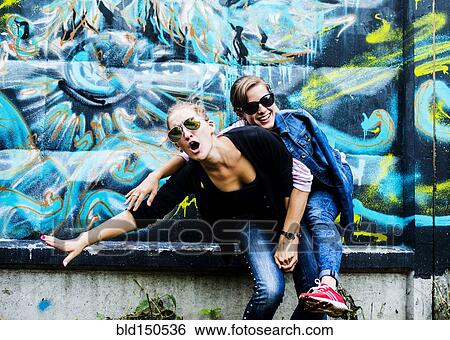 Caucasian women posing near graffiti wall View Large Photo Image Stock Photograph - Caucasian women posing near graffiti wall. Fotosearch