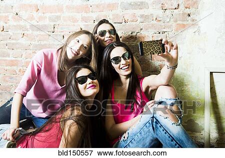 Stock Photo - Caucasian women taking cell phone selfie. Fotosearch