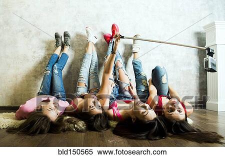 Stock Photography - Caucasian women taking cell phone selfie on floor. Fotosearch