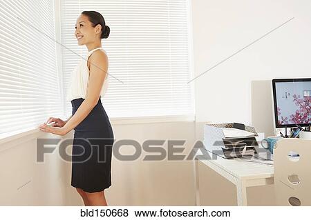 Chinese businesswoman looking out office window View Large Photo Image Stock Photo - Chinese businesswoman looking out office window. Fotosearch