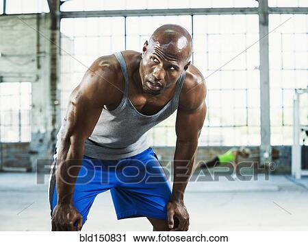 Stock Image - Close up of Black athlete resting in warehouse gym. Fotosearch