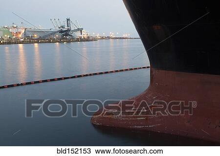 Stock Image - Close up of bow of ship docked in industrial harbor. Fotosearch