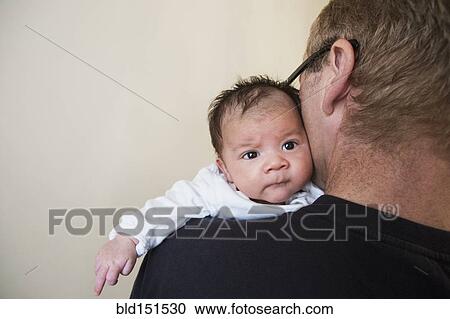 Stock Image - Close up of father holding mixed race baby. Fotosearch