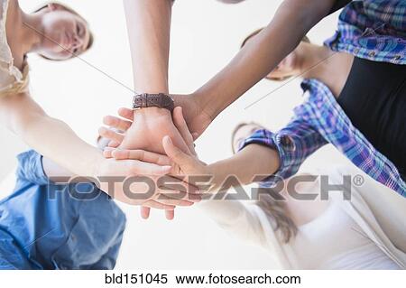 Stock Photography - Close up of teenagers stacking hands in huddle. Fotosearch