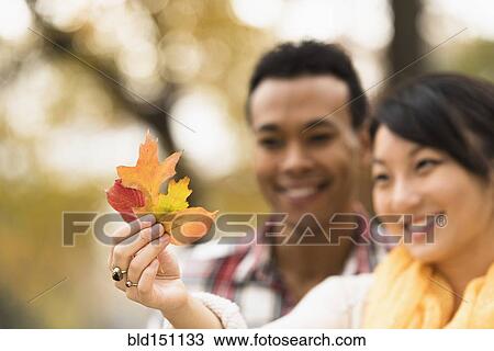 Stock Image - Couple admiring autumn leaves outdoors. Fotosearch