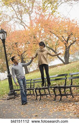 Couple playing on park bench View Large Photo Image Stock Image - Couple playing on park bench. Fotosearch