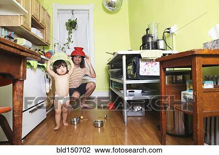 Stock Image - Father and daughter playing in kitchen. Fotosearch