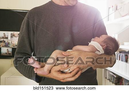 Stock Image - Father holding newborn baby in bedroom. Fotosearch