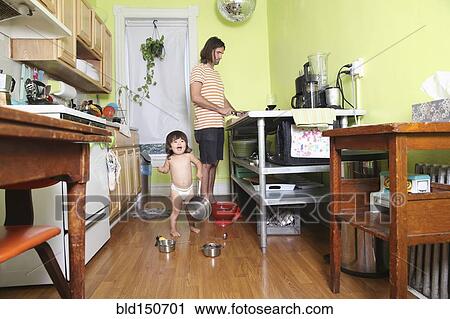 Girl playing in kitchen as father cooks View Large Photo Image Stock Image - Girl playing in kitchen as father cooks. Fotosearch
