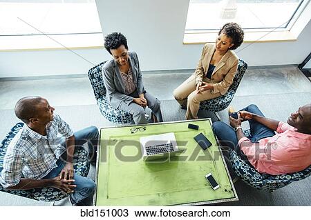 Stock Image - High angle view of business people talking in office lobby. Fotosearch