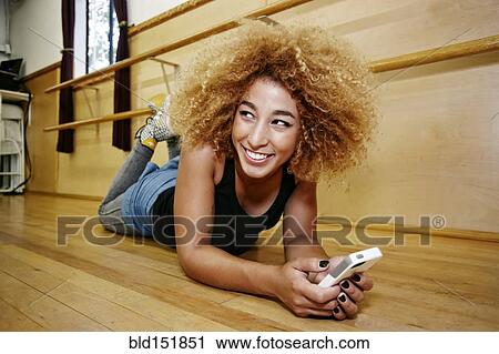 Stock Image - Hispanic dancer using cell phone in studio. Fotosearch