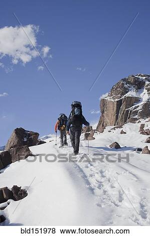 Stock Photo - Hispanic hikers walking on snowy mountain. Fotosearch