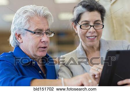 Hispanic teacher helping adult student use digital tablet View Large Photo Image Stock Image - Hispanic teacher helping adult student use digital tablet. Fotosearch