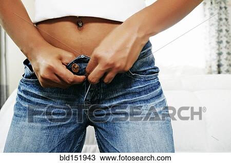 Stock Image - Hispanic woman buttoning jeans. Fotosearch