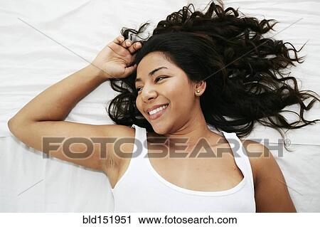 Stock Image - Hispanic woman laying on bed. Fotosearch