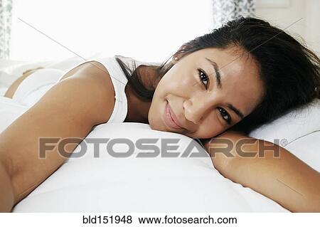 Stock Photo - Hispanic woman laying on bed. Fotosearch