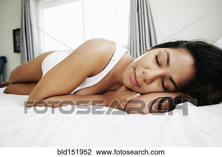 Stock Image - Hispanic woman sleeping on bed. Fotosearch