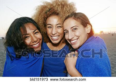 Stock Image - Hispanic women wrapped in blanket on beach. Fotosearch
