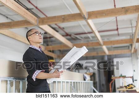 Korean architect holding blueprints and examining ceiling View Large Photo Image Stock Image - Korean architect holding blueprints and examining ceiling. Fotosearch