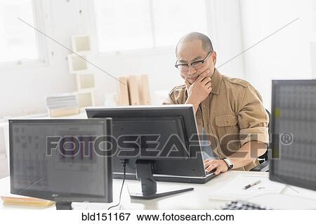 Korean businessman working on computer at office desk View Large Photo Image Stock Photo - Korean businessman working on computer at office desk. Fotosearch