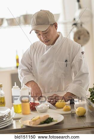 Stock Image - Korean chef slicing food in kitchen. Fotosearch
