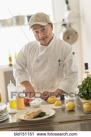 Stock Image - Korean chef slicing food in kitchen. Fotosearch