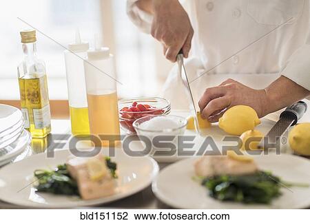 Stock Image - Korean chef slicing lemons in kitchen. Fotosearch