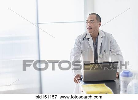 Korean doctor standing near laptop in office View Large Photo Image Stock Photo - Korean doctor standing near laptop in office. Fotosearch